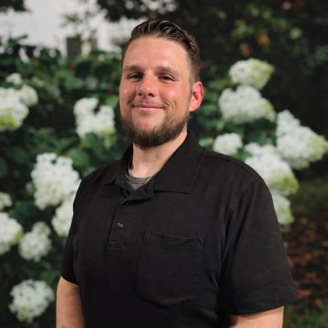 Man smiling in front of white hydrangea flowers