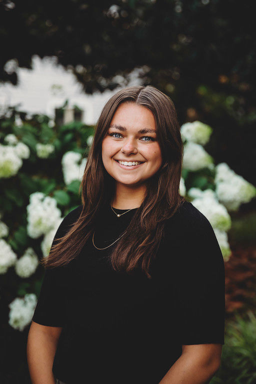 Smiling woman standing before white hydrangea flowers
